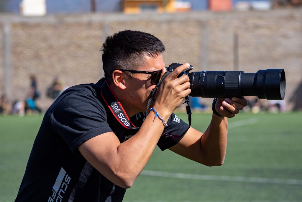 Photographer capturing moments at an outdoor sports event on a sunny day.